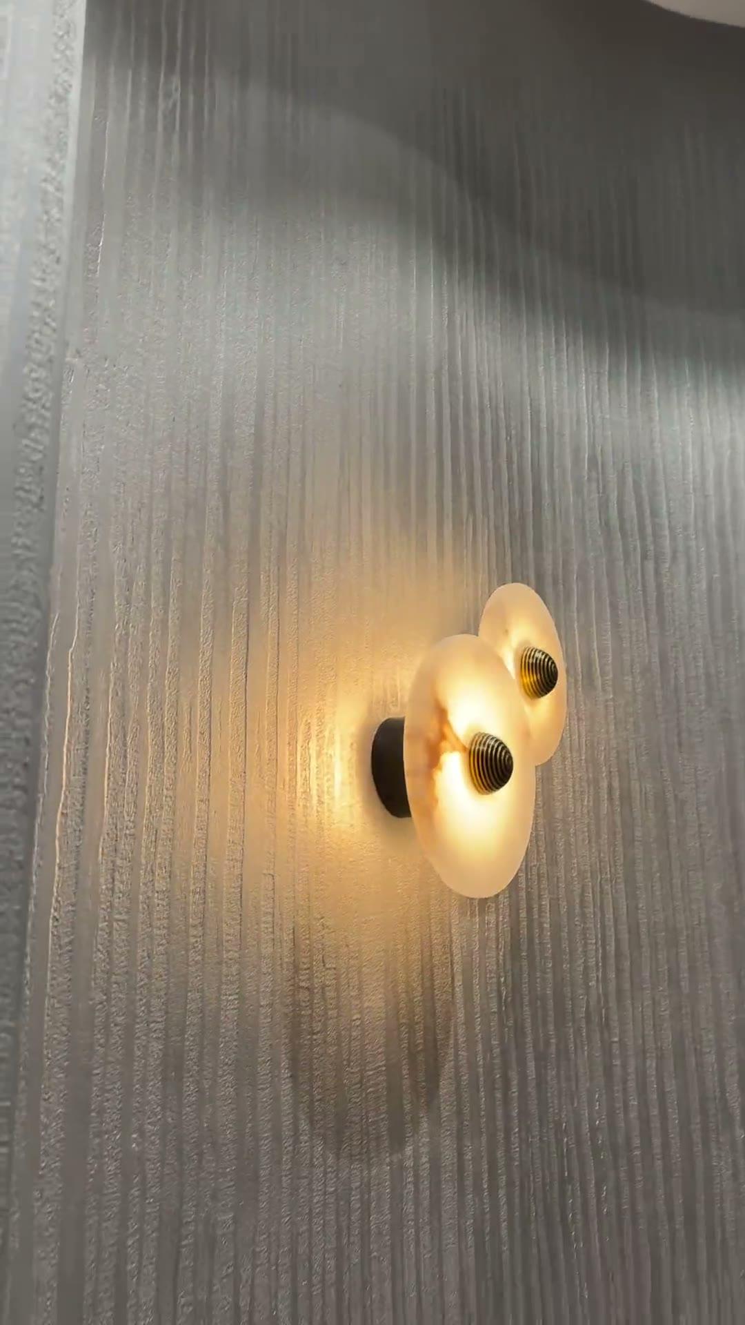 Bamboo texture under a grey metallic glaze in a powder room, light raking down the vertical grain beside alabaster wall lights and brass fittings